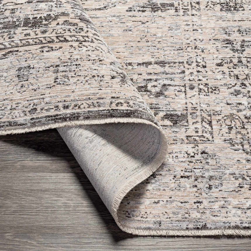 Close-up of the Divisoria Area Rug, a machine woven rug in charcoal, cream, and gray with a traditional pattern. Fold