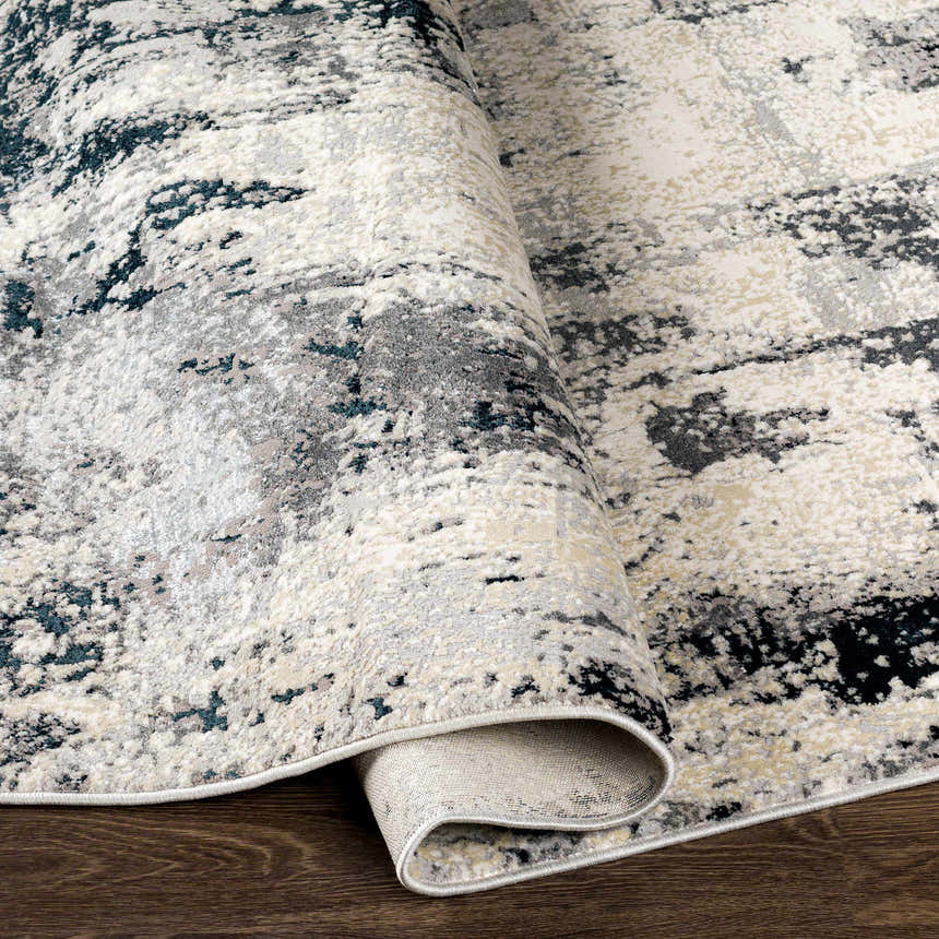Close-up of the Dumangas Area Rug, showing its black, charcoal, cream, and gray contemporary pattern and soft texture. Fold