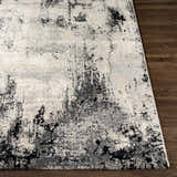 Close-up of the Dumangas Area Rug showing its abstract black, charcoal, cream, and gray pattern. Front