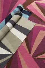 Close-up of rolled Dennis Area Rugs. Hand woven wool rugs in shades of aqua, blue, navy, sage, and pink. Contemporary style. Styleshot