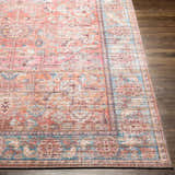 Close-up of Dormont Washable Area Rug, showing its coral, pink, and blue traditional pattern and soft chenille texture. Front