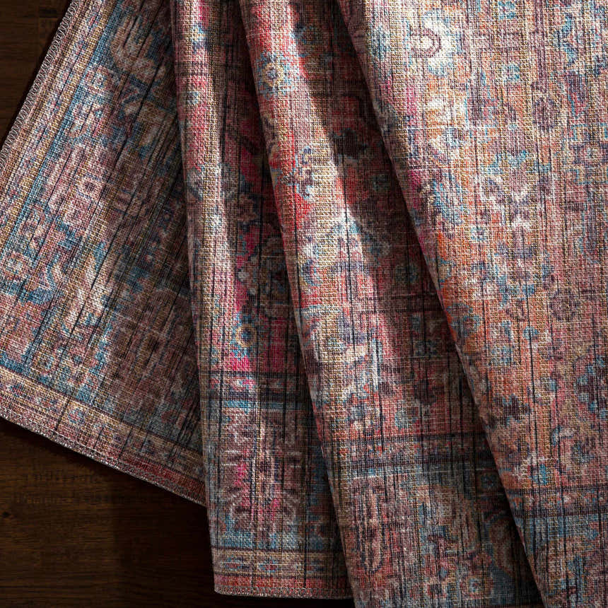 Close-up of the Dormont Washable Area Rug showing the chenille texture and colors of coral, denim, and tan. Fold