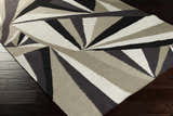 Close-up of the Dorset Area Carpet. Hand-woven wool rug with a contemporary geometric design in black, gray, and white tones. Corner