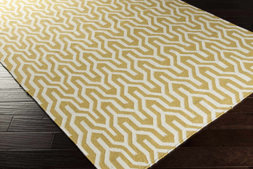 Close-up of the Drewryville Area Carpet. Tan and light gray geometric pattern on a hand woven wool rug. Corner