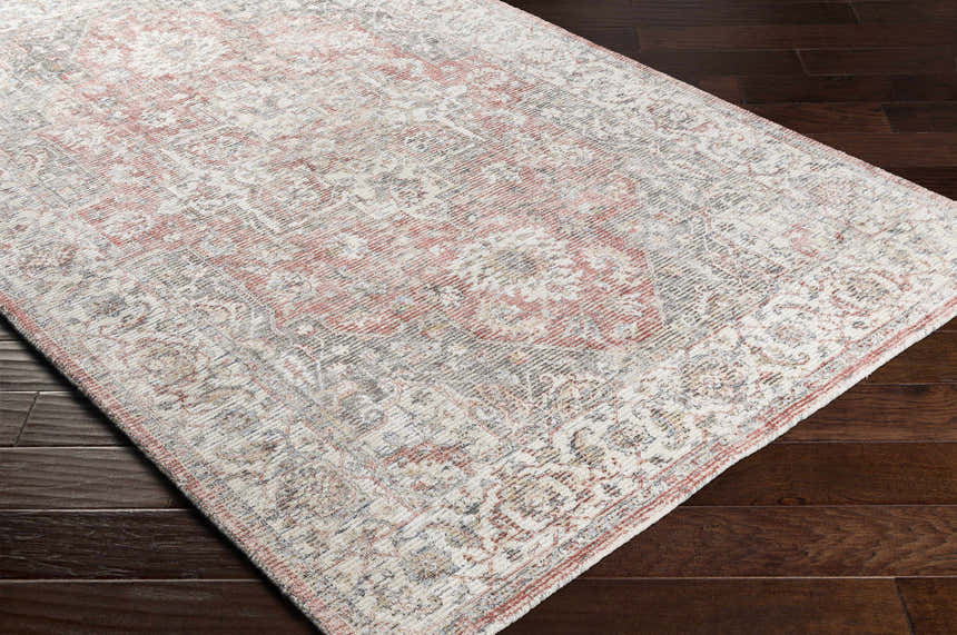 Close-up of the hand-knotted Dunmor Area Rug. Features a traditional Persian pattern in brick red, charcoal, and cream. Corner