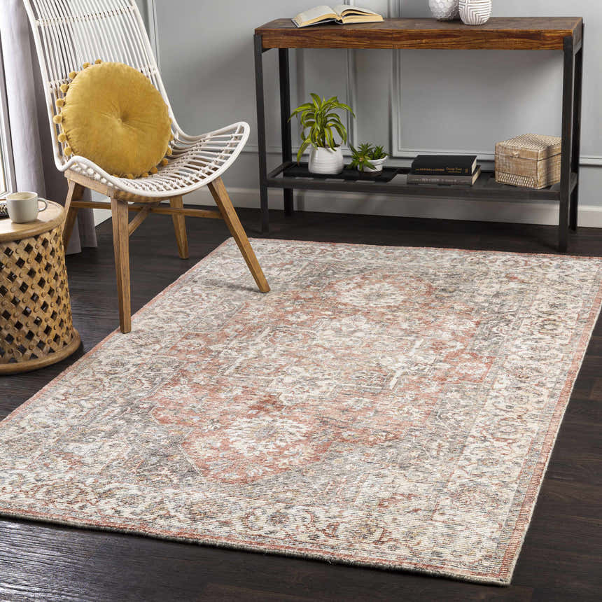 Living room scene with a brick red and cream Dunmor Area Rug, white chair, and dark wood floors. Roomscene-Rectangle