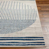 Close-up of the Duri Area Rug showing a geometric pattern in admiral blue and natural gray on a wood floor. Front
