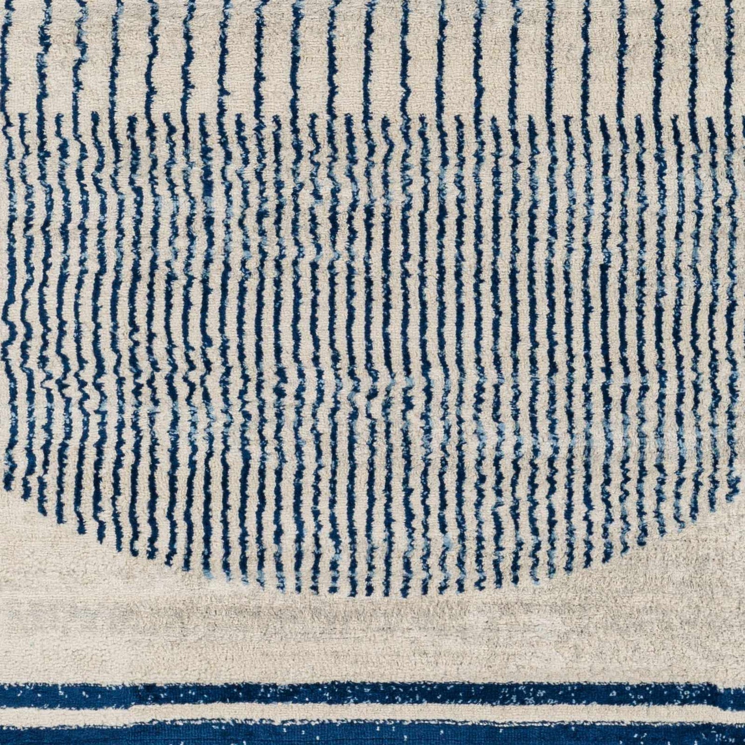 Close-up of the Duri Area Rug, featuring a geometric pattern with admiral blue stripes on a natural gray background. Swatch