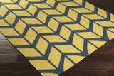 Close-up of the hand woven Eland Area Carpet. Dark blue geometric pattern on olive 100% wool rug. Corner