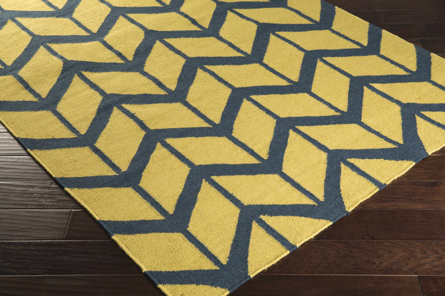 Close-up of the hand woven Eland Area Carpet. Dark blue geometric pattern on olive 100% wool rug. Corner