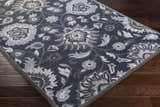 Close-up of the Conesus Hand Tufted Blue Area Rug showing its floral pattern and texture on dark wood flooring. Corner