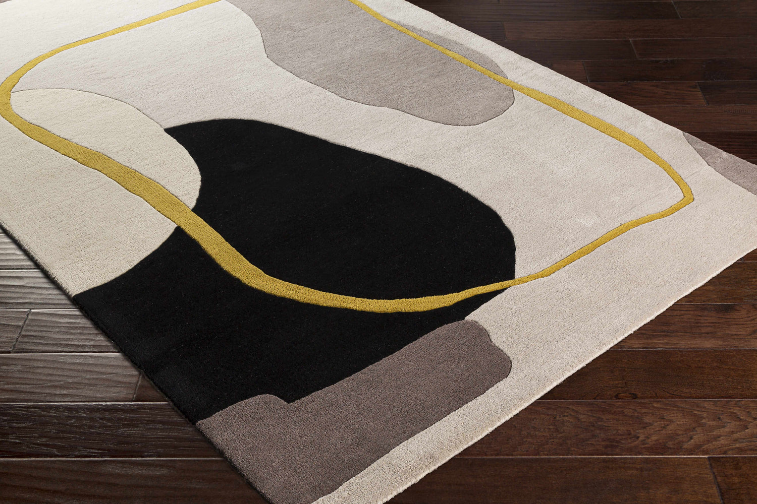 Close-up of the Elliminyt Area Rug. Hand-tufted wool rug with charcoal, gray, ivory, and mustard geometric shapes. Corner