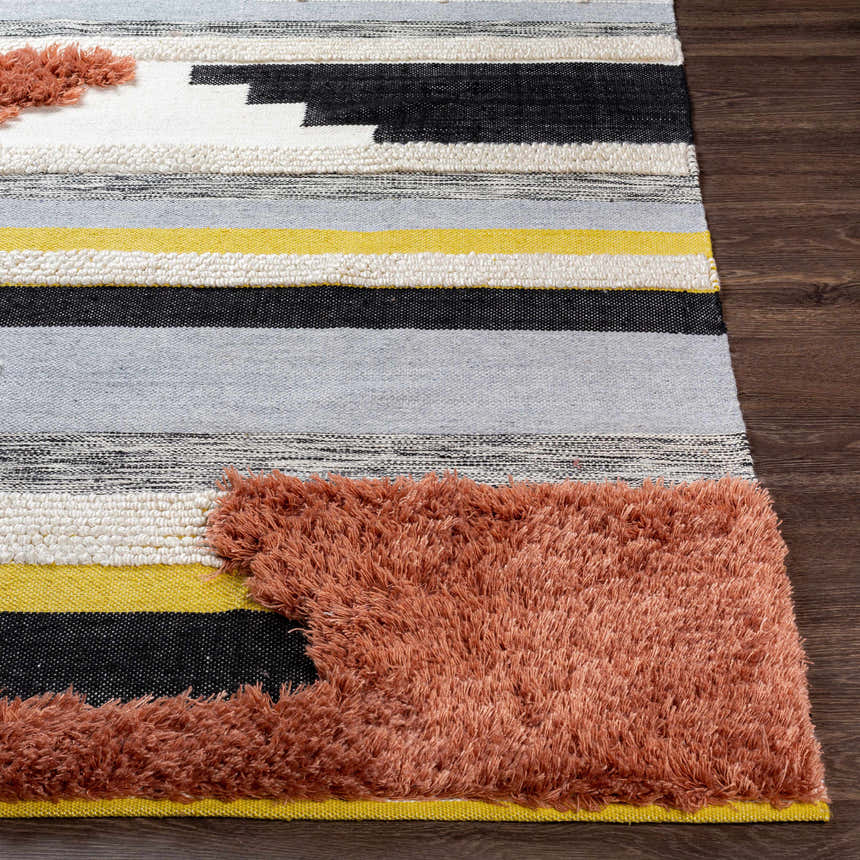 Close up of the Elsenham Area Rug with black, cream, gray, and mustard stripes and brick red shag detailing. Front