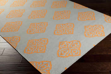 Close up of the Elwin Area Rug, oatmeal wool with orange geometric pattern. Corner