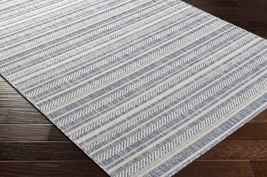 Close-up of Emirgazi Striped Nordic Rug with blue and off-white stripes on dark wood floor. Bohemian style. Corner