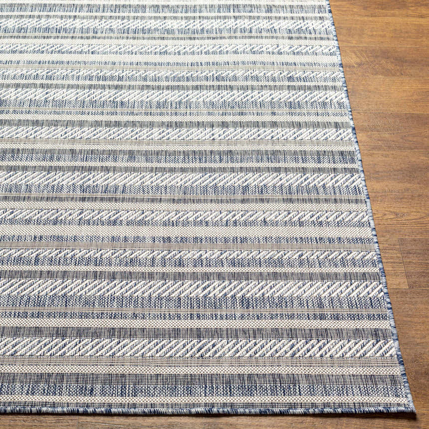 Close-up of the Emirgazi Striped Nordic Rug. Blue, gray, and oatmeal stripes with a subtle woven texture on wood floor. Front