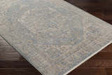 Close-up of the Tusa Blue Area Rug showing the traditional pattern and colors on a dark wood floor. Corner
