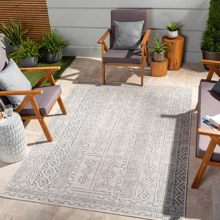 Outdoor patio scene with wood chairs and a blue and oatmeal Epson Indoor & Outdoor Rug. Roomscene-Rectangle