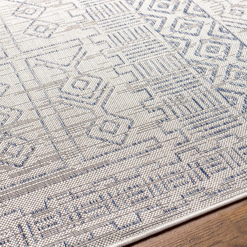 Close-up of the Epson Indoor & Outdoor Rug with a geometric pattern in blue, gray, and oatmeal. Machine woven texture. Texture