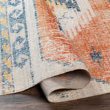 Close-up of the Etobicoke Area Rug, showcasing its brick red, denim, and cream Southwestern-inspired design. Fold