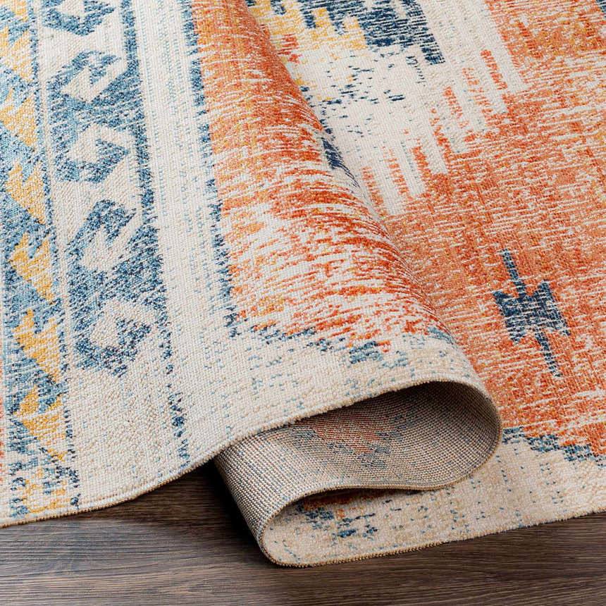Close-up of the Etobicoke Area Rug, showcasing its brick red, denim, and cream Southwestern-inspired design. Fold