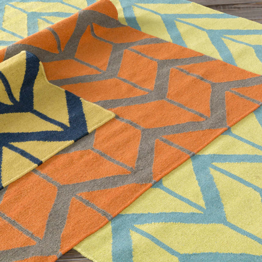 Close-up of Eland Area Carpet showing geometric pattern in dark blue, olive, and orange wool. Hand woven texture. Styleshot