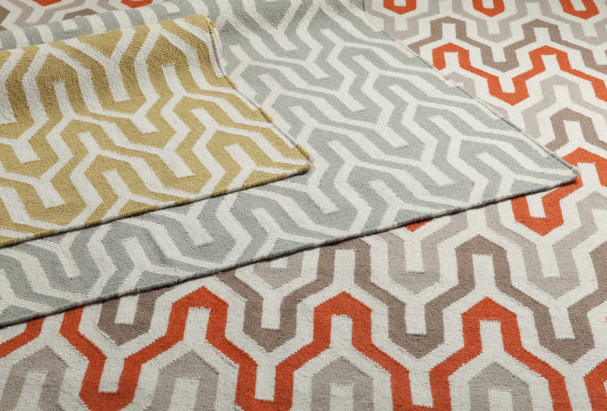 Close-up of Drewryville Area Carpet showing geometric pattern in light gray, tan, and orange wool. Hand woven texture. Styleshot
