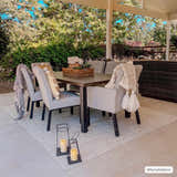 Outdoor dining area with a Beige Braided Faux Jute Rug under a table and chairs. Neutral tones and natural light. Roomscene-Rectangle