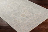 Close-up of the Coby Sage Avant Garde rug. Machine-woven polyester rug in brown, charcoal, sage, and gray on dark wood floors. Corner