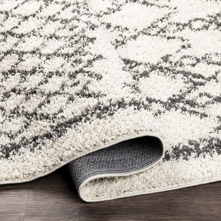 Close up of the charcoal and cream Fenstanton Area Rug, a shag rug with a contemporary geometric pattern. Fold
