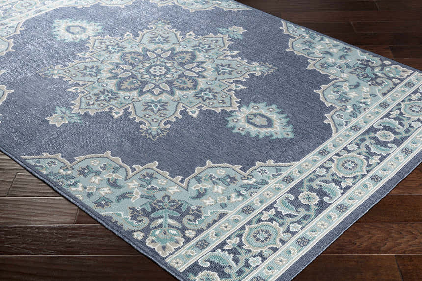Close-up of the Ferron Area Rug. Navy olefin rug with pale blue, taupe, and teal floral medallion and border design. Corner