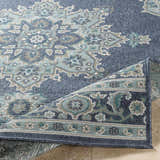 Close-up of the Ferron Area Rug, showing a traditional oriental pattern in navy, pale blue, taupe, teal, and white. Fold
