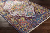 Close-up of the hand-knotted Flagtown Area Rug. Bohemian style with blue, burgundy, and mustard colors on dark wood floors. Corner