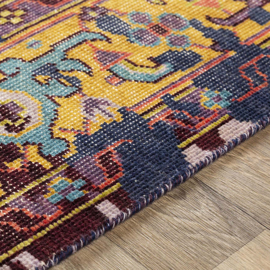 Close-up of the hand-knotted Flagtown Area Rug. Features a traditional, colorful pattern in blue, burgundy, and mustard hues. Pile