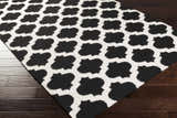 Close-up of the Fleetville Area Rug, a hand-woven wool rug with a bold black and ivory geometric pattern. Corner