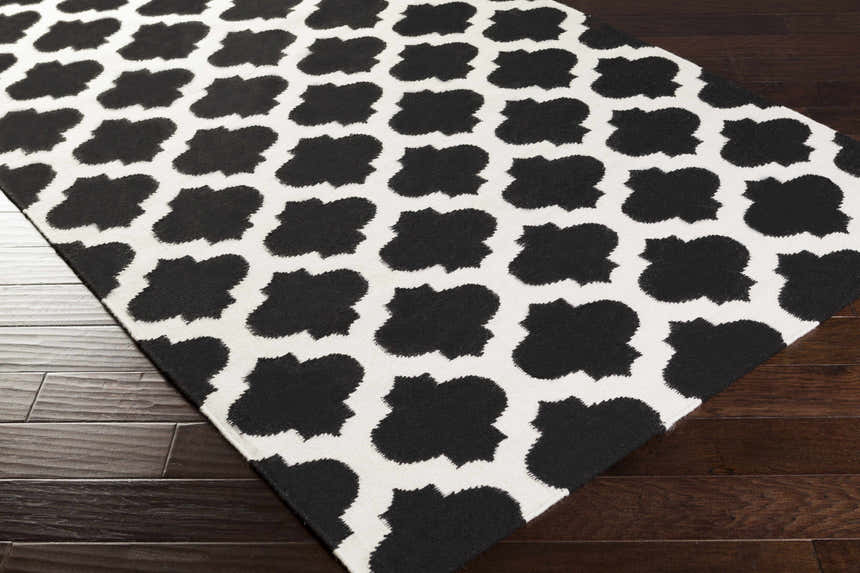 Close-up of the Fleetville Area Rug, a hand-woven wool rug with a bold black and ivory geometric pattern. Corner