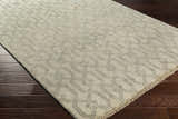 Close-up of the Fairborn Wool Rug. Taupe rug with charcoal geometric pattern on dark wood floor. Hand-knotted texture. Corner