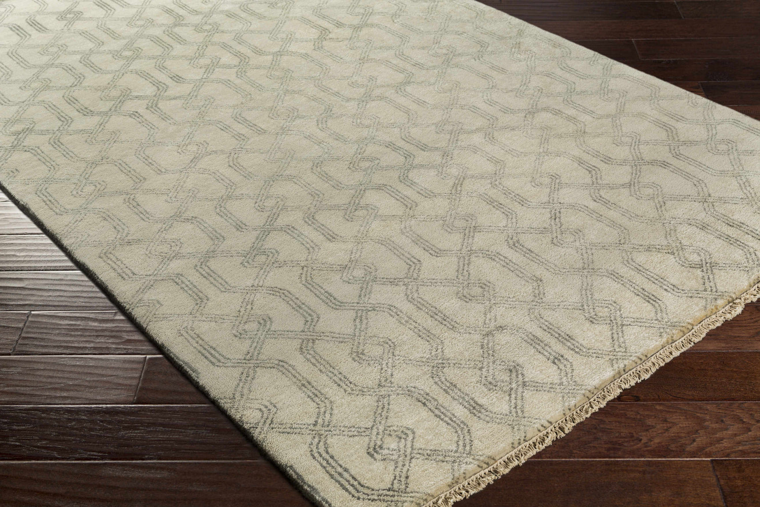 Close-up of the Fairborn Wool Rug. Taupe rug with charcoal geometric pattern on dark wood floor. Hand-knotted texture. Corner