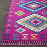 Close-up of Franktown Magenta Carpet. Bohemian style rug with aqua, blue, camel, and fuchsia geometric patterns and tassels. Front