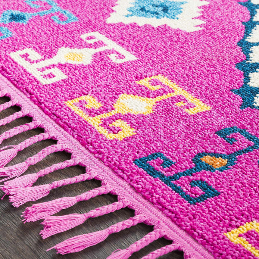Close-up of the Franktown Magenta Carpet showing its bohemian design, tassels, and bright fuchsia, blue, and yellow colors. Texture