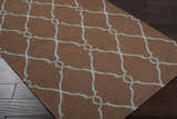 Close-up of the Frost Area Rug, a brown wool rug with a dusty sage geometric trellis pattern. Corner