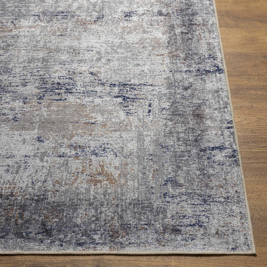 Close-up of Fairplains Washable Area Rug. Features a vintage design with charcoal, gray, dark blue, and brown tones. Front