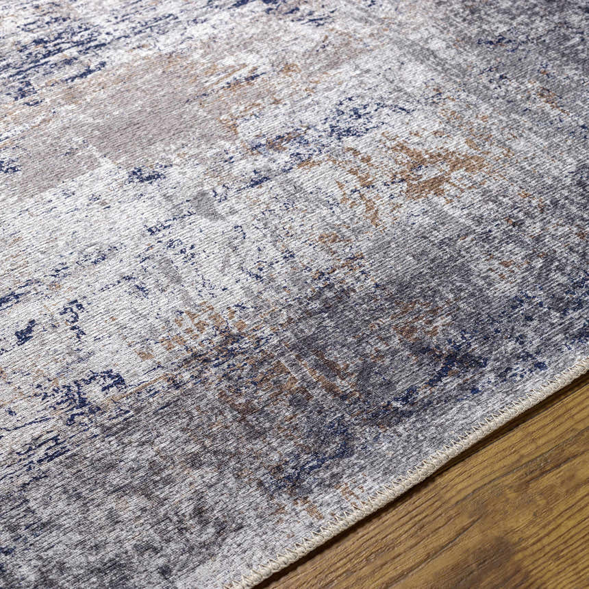 Close-up of Fairplains Washable Area Rug showing charcoal, navy, gray, and brown abstract pattern and woven texture. Texture