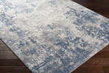 Close-up of the Fruitland Area Rug. Blue, charcoal, gray, and off-white abstract pattern. Machine woven texture. Corner