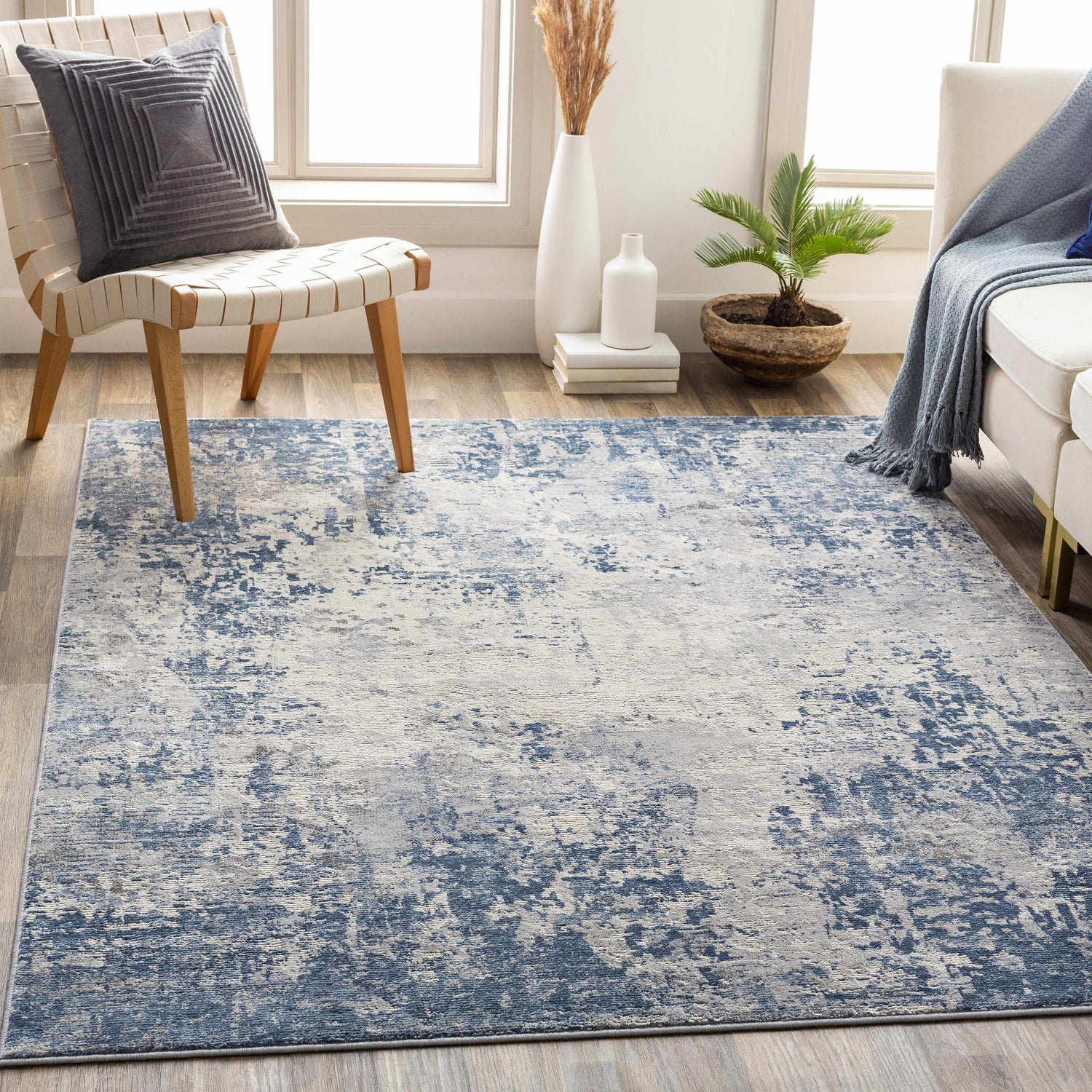 Living room scene with a blue and gray Fruitland Area Rug, white sofa, and modern chair. Roomscene-Rectangle
