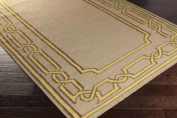 Close-up of the Fruitvale Area Rug. Tan wool rug with a dark brown and taupe geometric border. Corner