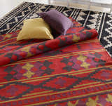 Styled Gratiot Area Rug. Hand woven rug in black, gray, red, purple, and gold with geometric patterns. Pillows add texture. Styleshot