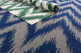 Parsonsfield Area Rug - Clearance, showing green and cream rug partially rolled on top of blue and gray rug. Styleshot