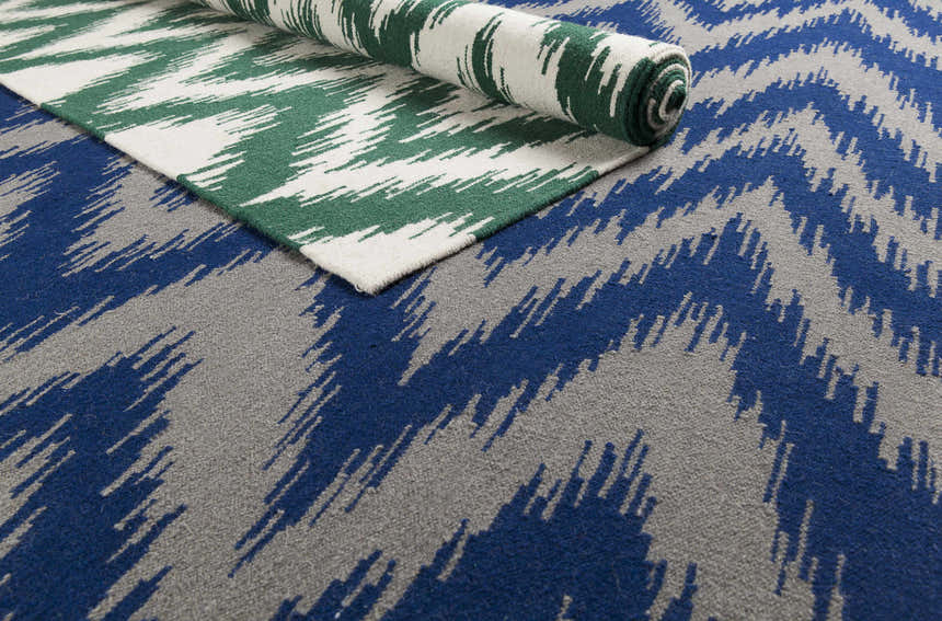 Parsonsfield Area Rug - Clearance, showing green and cream rug partially rolled on top of blue and gray rug. Styleshot