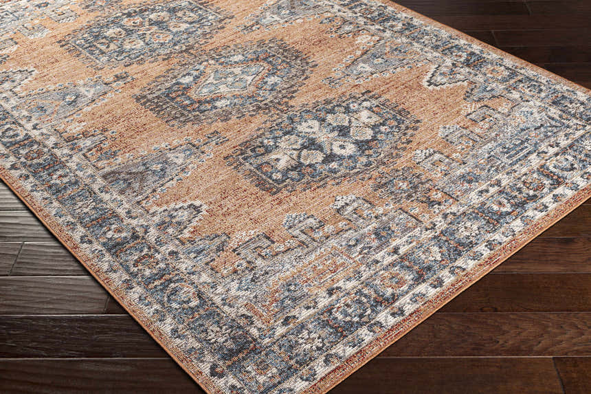 Close-up of the Fullarton Performance Rug showing its beige, blue, and brick red traditional pattern on dark wood floors. Corner